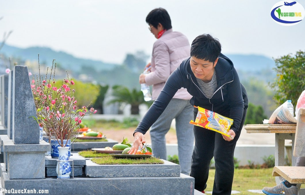 alt text: Người phụ nữ đang thắp hương tại mộ phần